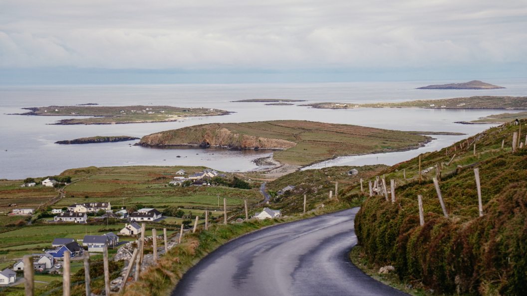 Strada costiera tortuosa con vista su isole e terre agricole a Connemara, nella contea di Galway.