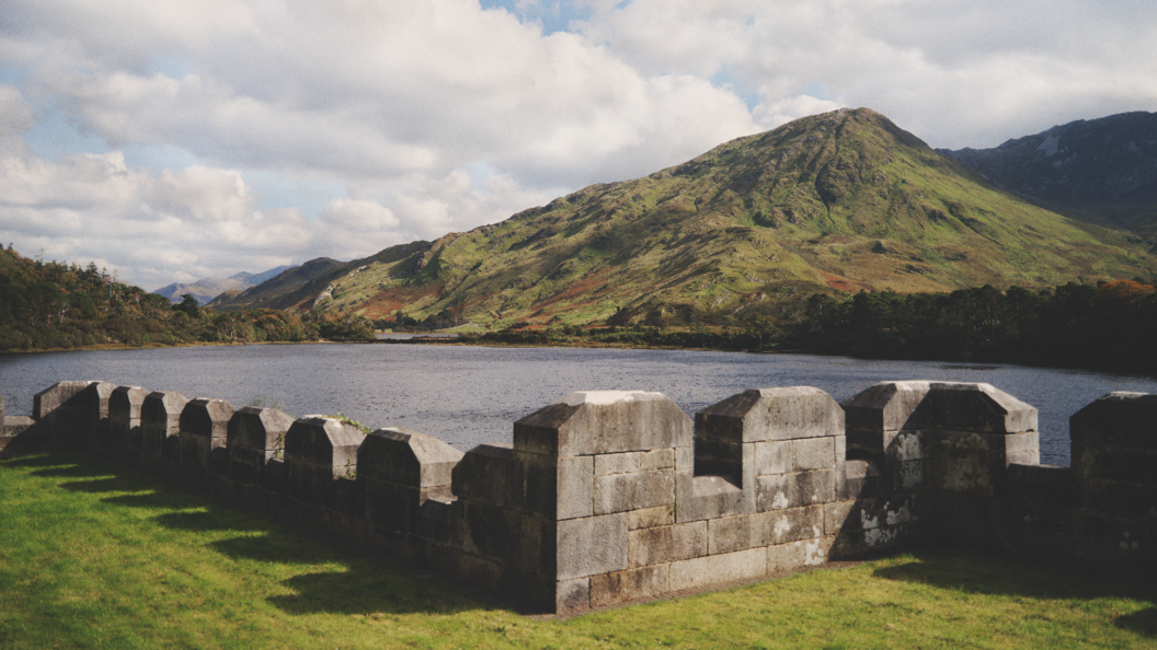 Vista dall'Abbazia di Kylemore attraverso un lago verso le verdi montagne del Connemara nella contea di Galway.