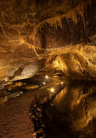 Walkway through Marble Arch Caves with stalactites overhead and underground river pools in County Fermanagh.