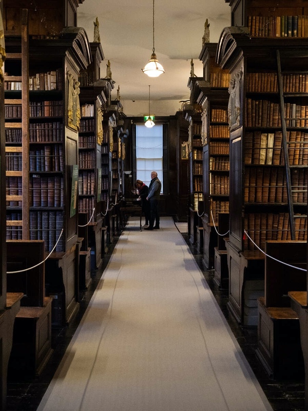 Ornate wooden reading cages with arched lattice doors and old books in Marsh's Library, Dublin.
