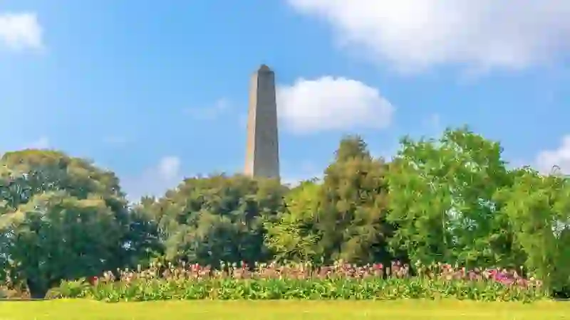 Wellington Monument rising above trees and colourful flowerbeds in Phoenix Park, Dublin.