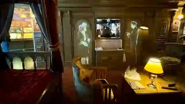 Nachbildung einer First-Class-Kabine im Stil der damaligen Zeit im Titanic Belfast mit Vintage-Möbeln und projizierten Figuren.