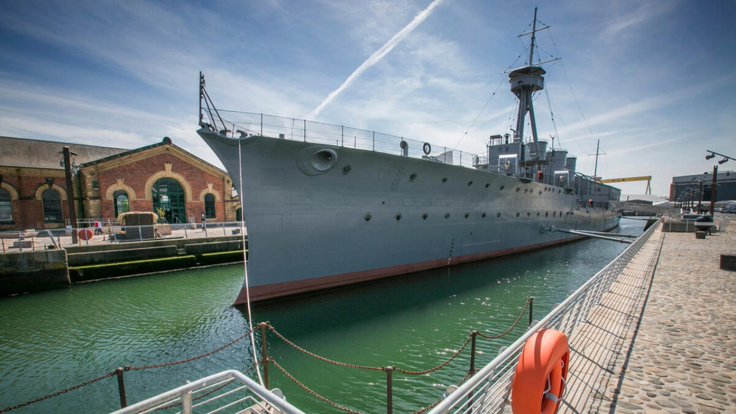 La HMS Caroline ormeggiata nel Titanic Quarter di Belfast, accanto agli storici edifici dell'Alexandra Dock