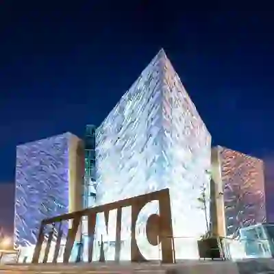 Titanic Belfast illuminato di notte, con la sua facciata argentata angolare e l'iconico cartello del Titanic a Belfast, nella contea di Antrim.