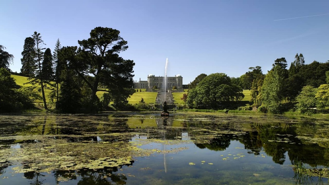 Powerscourt Estate and gardens reflected in a tranquil lake beneath the Wicklow Mountains, County Wicklow.
