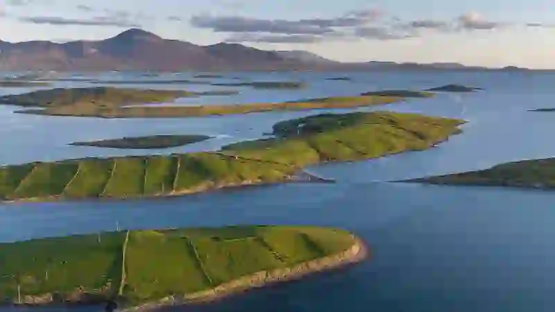 Vista aérea de las islas verdes de la bahía de Clew con Croagh Patrick al fondo al atardecer.