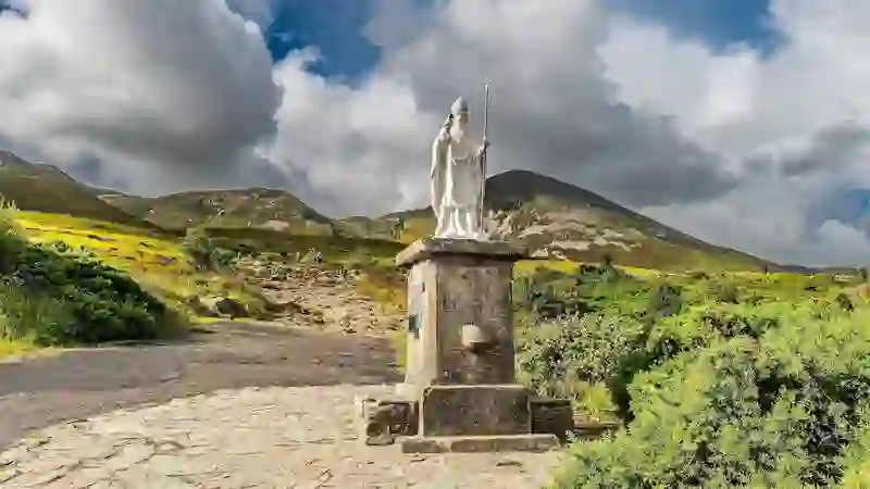 Estatua de San Patricio al pie del Croagh Patrick, con las escarpadas montañas al fondo.