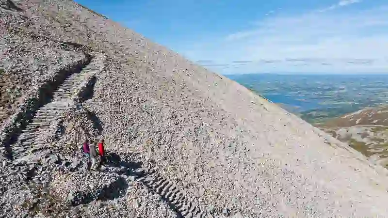 Los excursionistas bajan por el camino rocoso de Croagh Patrick con vistas panorámicas de la bahía de Clew.
