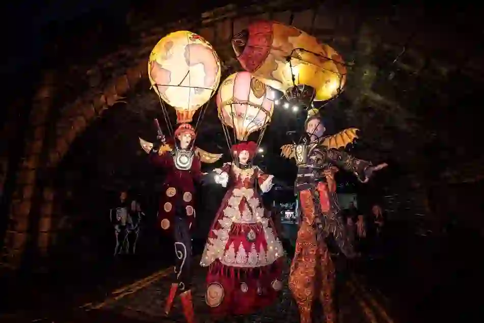 Des artistes en costume, perchés sur des échasses et accompagnés de montgolfières illuminées, défilent dans les rues de Derry~Londonderry à l'occasion d'Halloween.