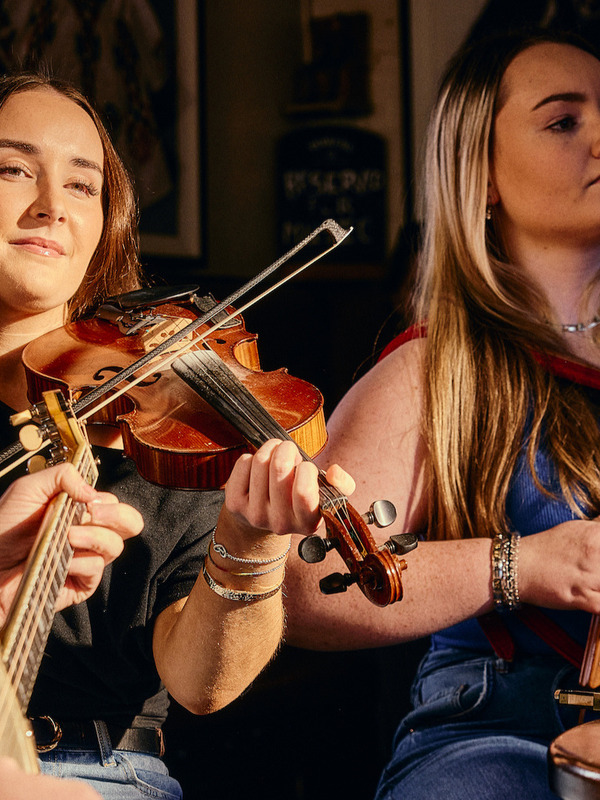 Traditional Irish music session with fiddle, banjo and accordion players performing in a cosy Belfast pub.