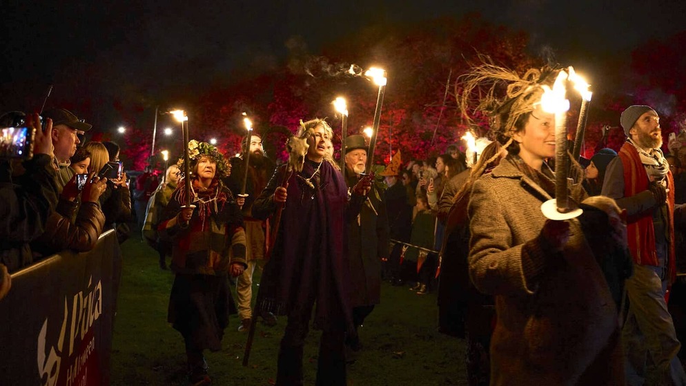 Crowds watch performers carrying flaming torches during the Púca Festival night parade in Ireland.