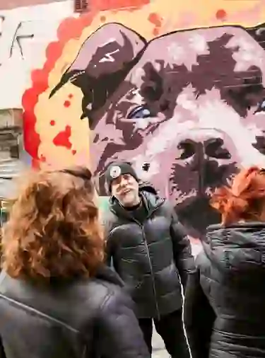 Un guía charla con los visitantes junto a un llamativo mural de un perro en un callejón de Belfast durante una visita guiada de arte urbano.