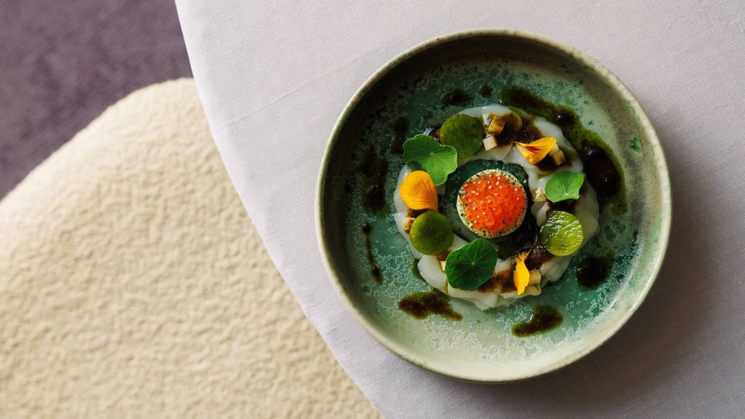 Gourmet seafood dish with herbs, edible flowers and roe served in an artisan ceramic bowl at Gregan's Castle, County Clare.