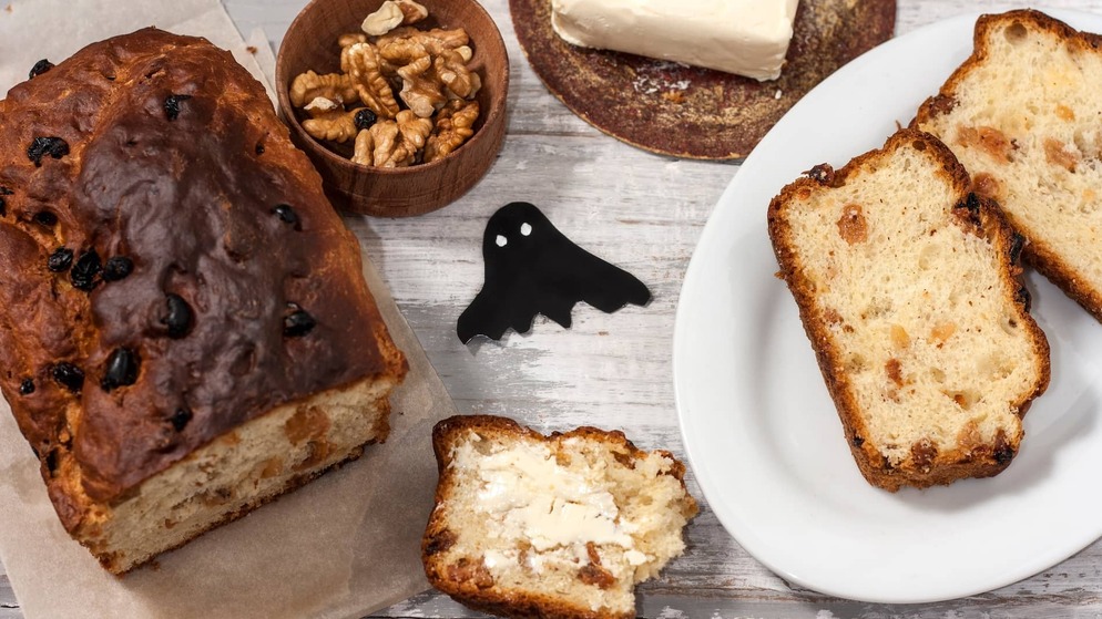 Traditional Irish barmbrack served with butter, sliced and ready to enjoy, alongside walnuts and dried fruit.