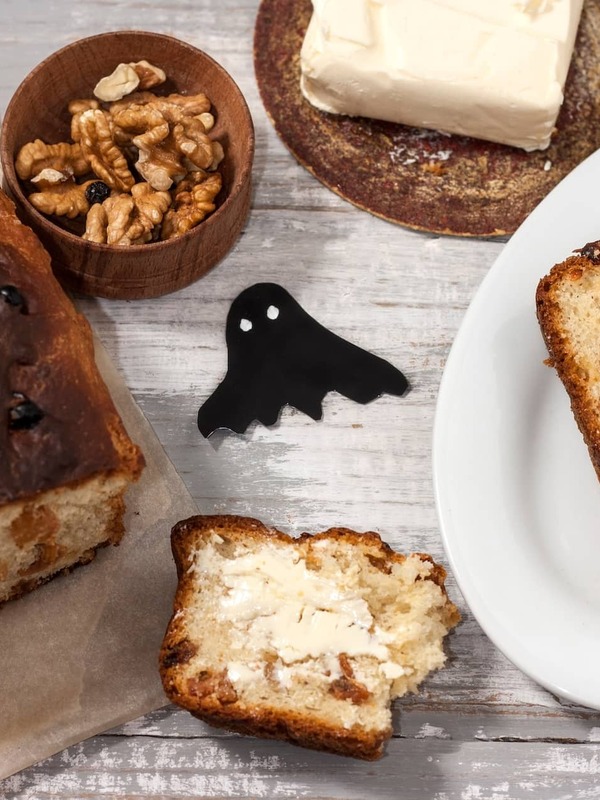 Traditional Irish barmbrack served with butter, sliced and ready to enjoy, alongside walnuts and dried fruit.