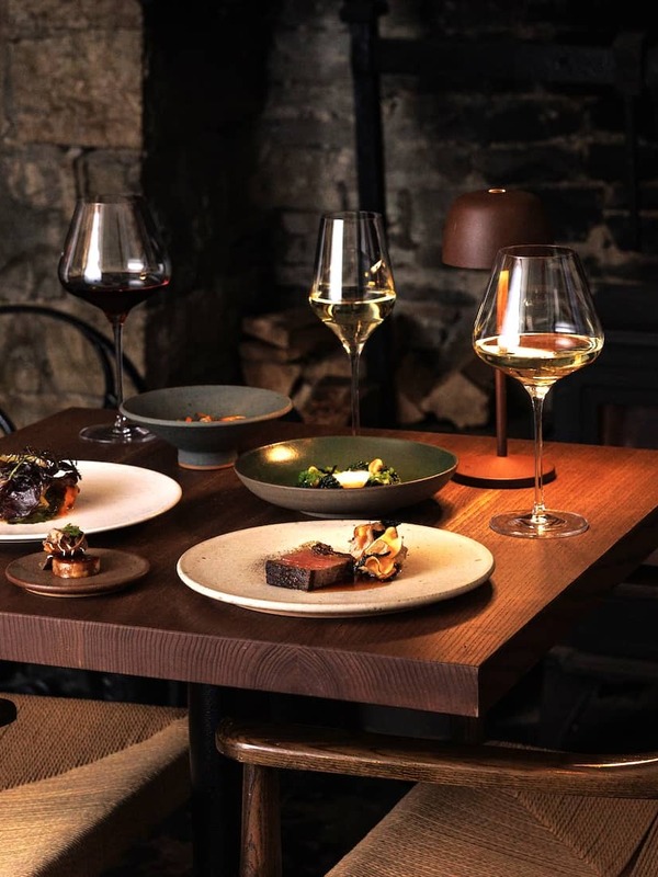 Elegant dining table at Homestead Cottage restaurant, County Clare, with fine food and wine beside a glowing fireplace.