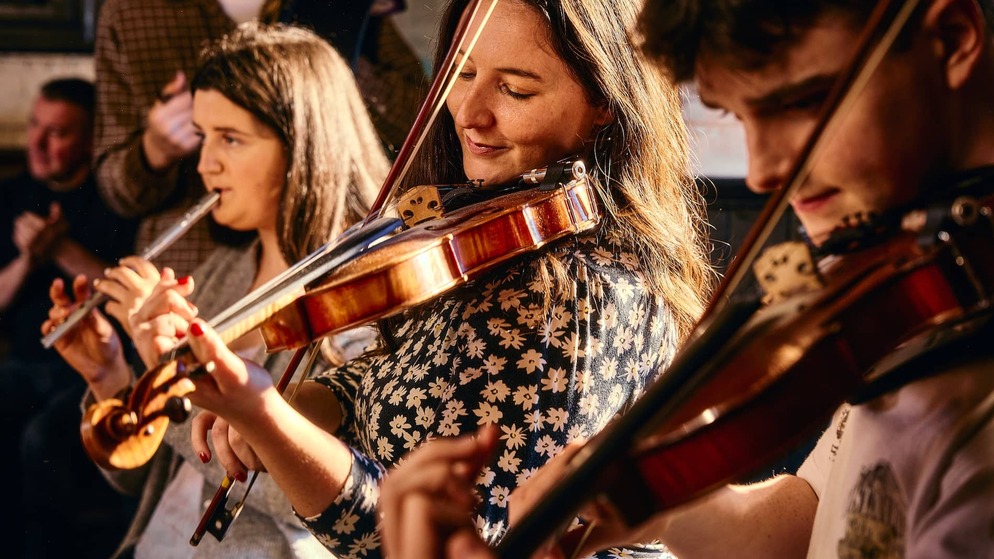 Traditional Irish musicians perform a lively session in a cosy pub in Belfast.