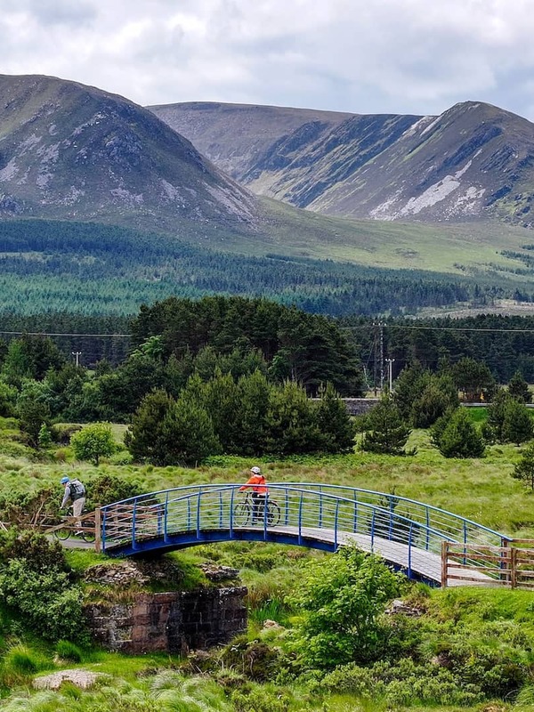 Cyclists cross a bridge on the Great Western Greenway with Croagh Patrick in County Mayo beyond.