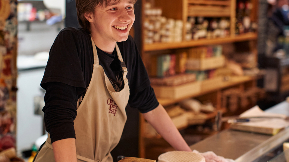 Cheesemonger serving customers at The English Market in Cork City with artisan Irish cheeses on display.