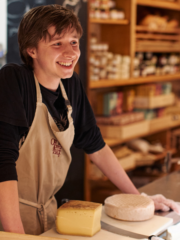 Cheesemonger serving customers at The English Market in Cork City with artisan Irish cheeses on display.