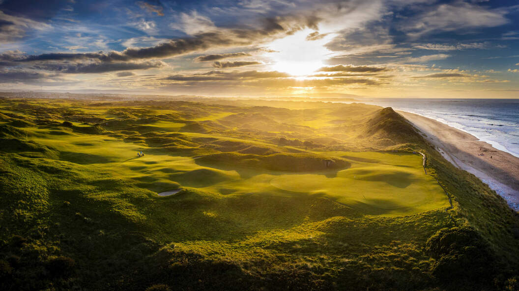 Golden sunlight casts long shadows across Royal Portrush Golf Course and the nearby beach on Antrim’s dramatic coastline.