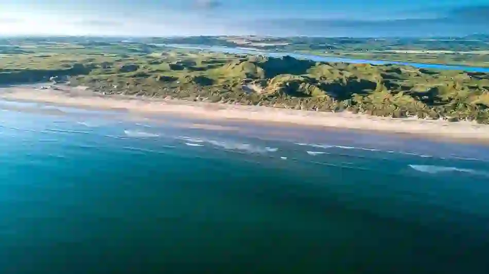 Aerial view of Portstewart Golf Club's links course beside a long sandy beach in County Londonderry.
