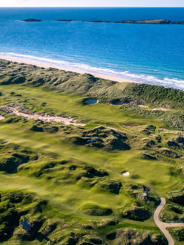 Vue aérienne du Royal Portrush Golf Club avec des fairways ondulants donnant sur l’océan Atlantique.