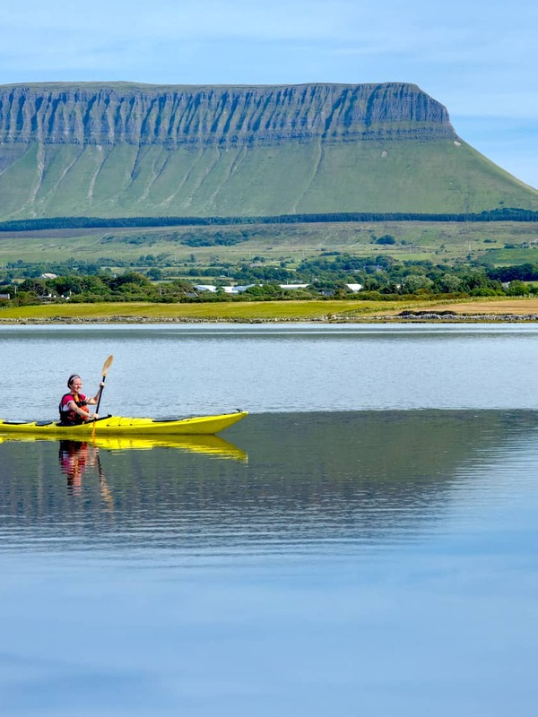 Personne faisant du kayak sur des eaux calmes avec le Ben Bulben en arrière-plan, dans le comté de Sligo.