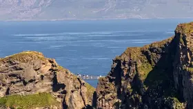 Clifftop views of Carrick-a-Rede with the rope bridge visible above turquoise water and distant headlands in County Antrim.