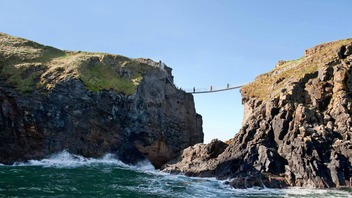 Bezoekers steken de Carrick-a-Rede-hangbrug over in county Antrim, die tussen dramatische zeekliffen boven de Atlantische Oceaan hangt.