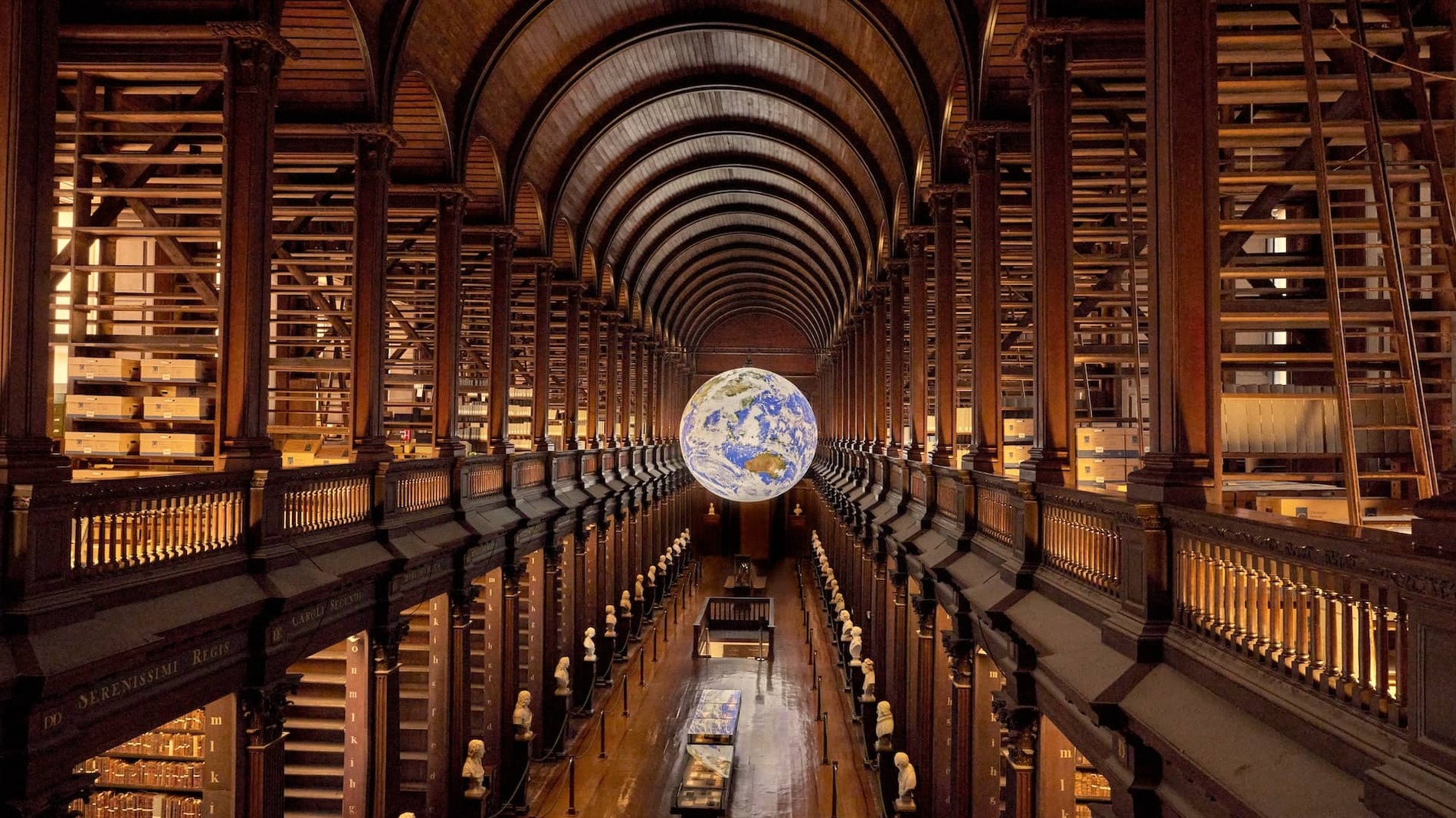 Grand vaulted Long Room at Trinity College Dublin with wooden arches, book-lined galleries, and a suspended illuminated globe.