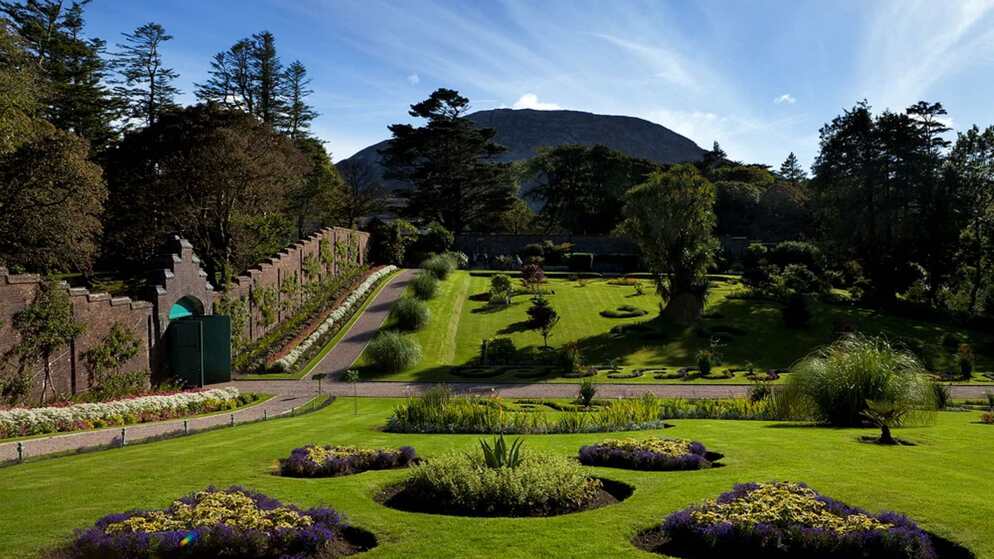 Historic walled garden with manicured lawns and mountain backdrop in Ireland.