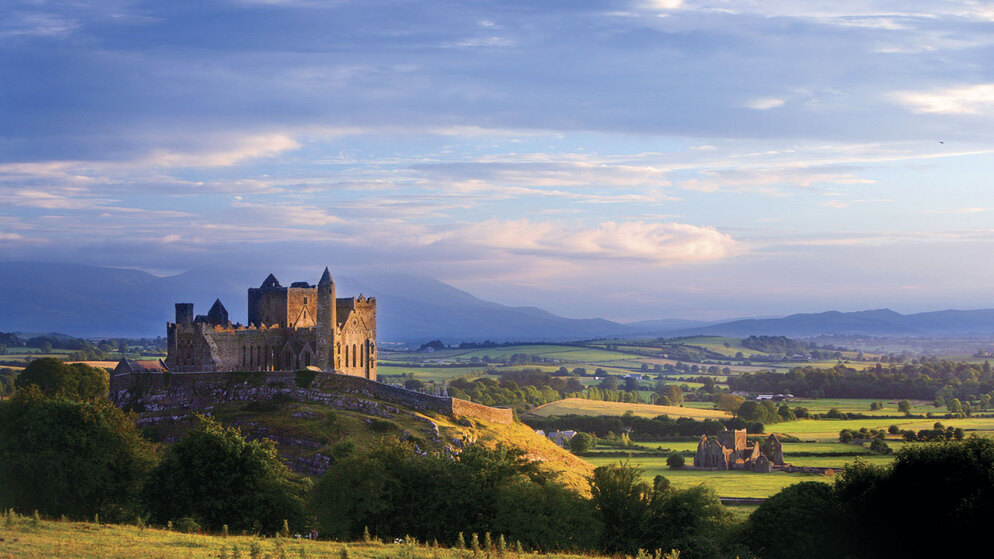 Rock of Cashel bei Sonnenuntergang mit Feldern und Hügellandschaft in der Grafschaft Tipperary, Irland.