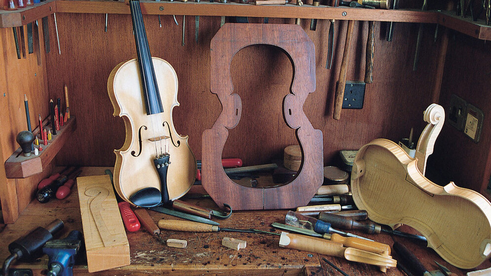Banc d'atelier avec violon, outils et pièces de cadre montrant l'artisanat de la fabrication d'instruments irlandais.